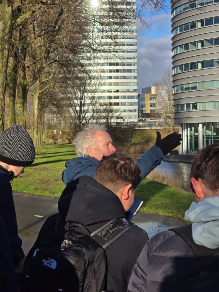 Kaj Munk College-leerlingen tijdens een excursie naar station Hoofddorp, waar ze het kunstwerk Moed! en de omgeving observeren om inspiratie op te doen voor hun ontwerpen.